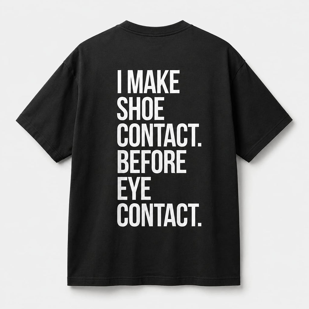 Back view of SNKR HEAD oversized off black t-shirt featuring I Make Shoe Contact Before Eye Contact typography graphic.