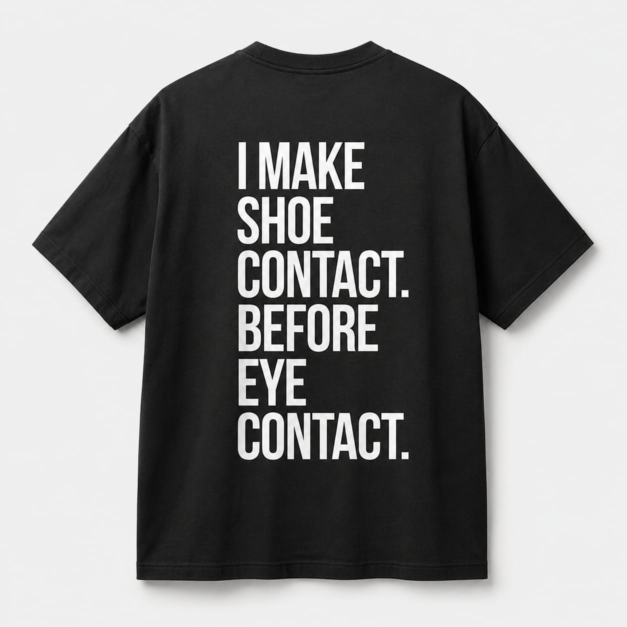 Back view of SNKR HEAD oversized off black t-shirt featuring I Make Shoe Contact Before Eye Contact typography graphic.